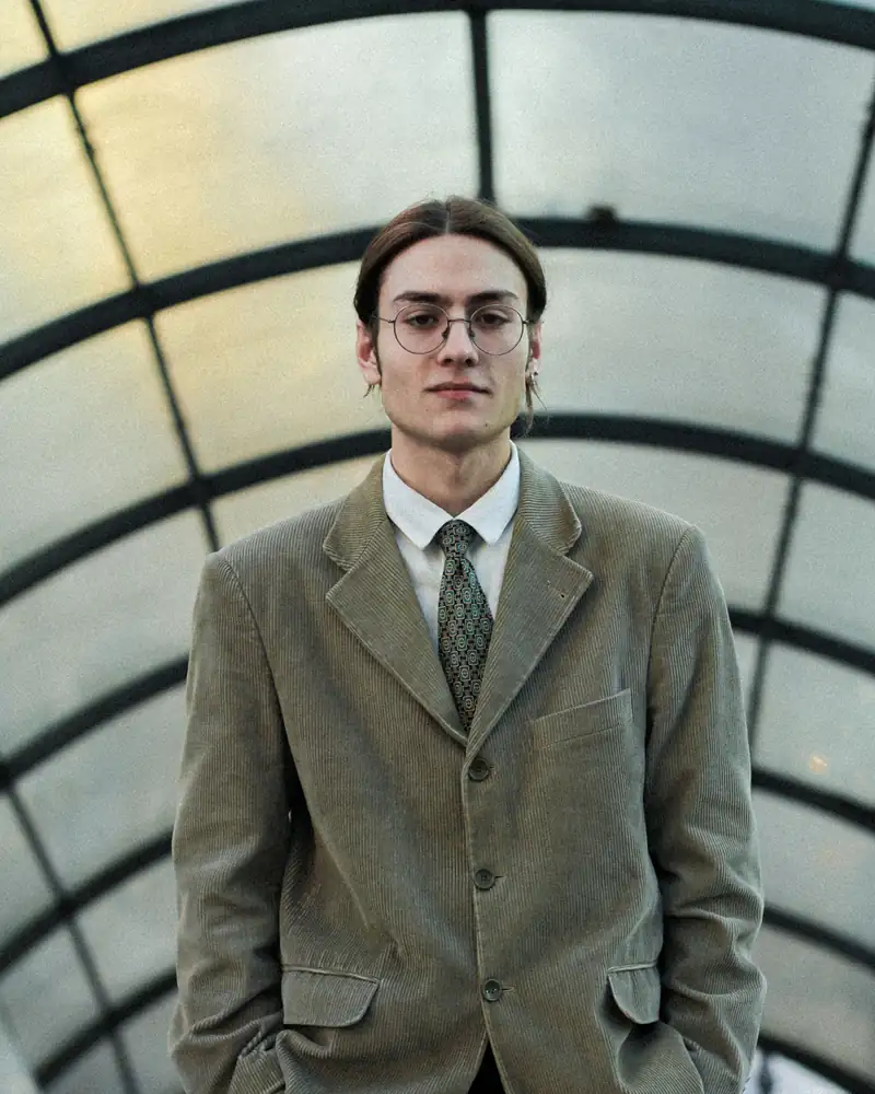 A man in a tweed jacket standing under a glass roof
