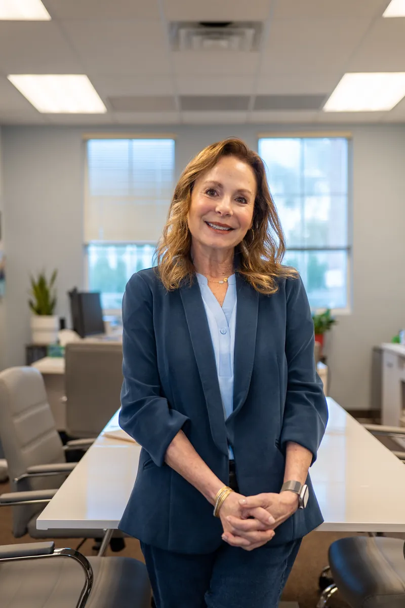 A woman in a navy blazer standing in an open-plan office