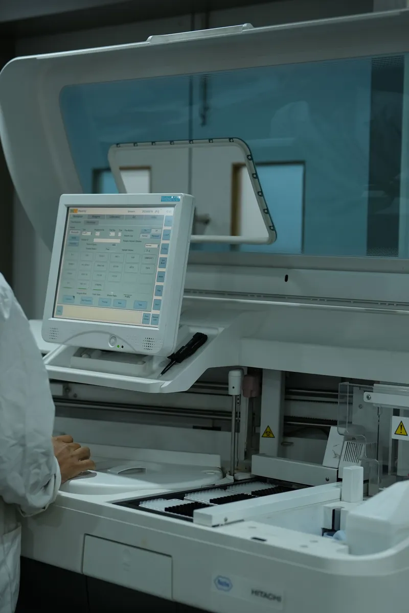 A laboratory analyser with a technician working behind it